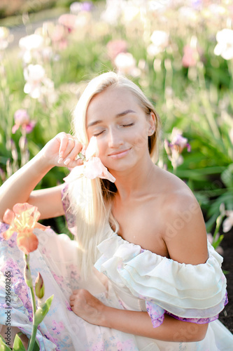 Young smiling woman sitting near irises on garden. photo