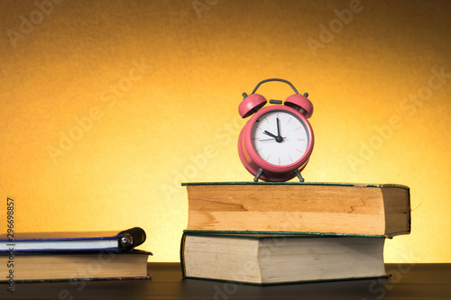 Symbolic hard study is powerful to succeed, concept with book and alarm clock. Time in business and quality