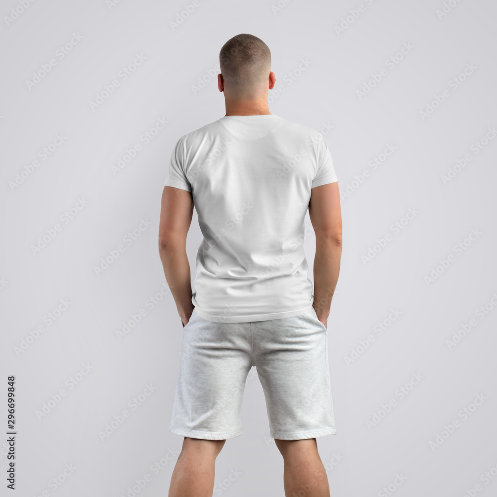 Muscular young caucasian man in a blank T-shirt on a white background. Back pose. Muscular young caucasian man in a blank T-shirt on a white background. Back pose.