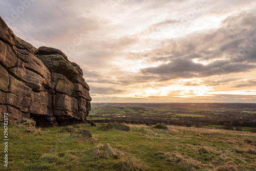 Almscliffe Crag overlooking farm fields during a dramatic sunset.