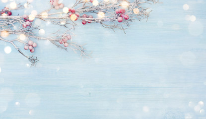 Snowy branch with red berries over abstract blue wooden background