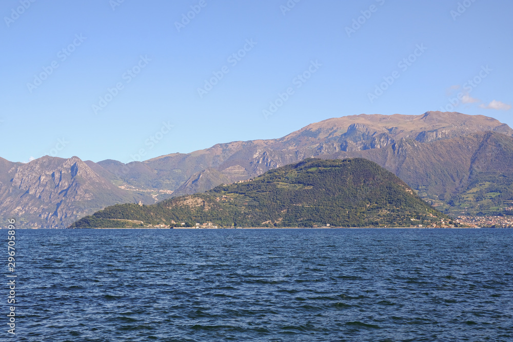 Landscape of Iseo Lake. View of the island Montisola. Alpine lake during a sunny day with a blue sky. Landscape of Iseo Lake. View of the island Montisola. Alpine lake during a sunny day with a blue sky.