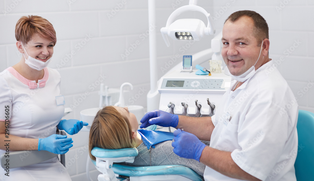 Doctor dentist treats teeth of a beautiful young girl patient. The girl on reception at the dentist. Doctor dentist treats tooth Doctor dentist treats teeth of a beautiful young girl patient. The girl on reception at the dentist. Doctor dentist treats tooth