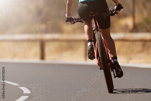 Active sports woman riding mountain bike in the nature on asphalt road