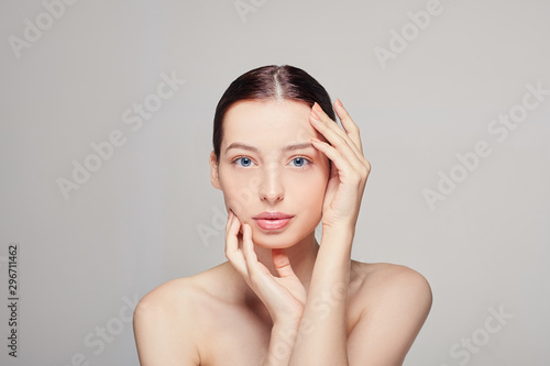 Beauty Woman face Portrait. Beautiful Spa model Girl with Perfect Fresh Clean Skin. Brunette female touch her face by both her hands. Youth and Skin care