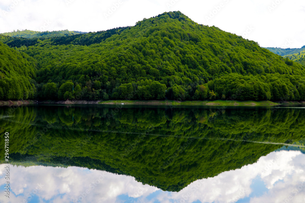 View of the high green hill, mountain. Reflection in water. Out of focus. A clear sunny day. Nature background.