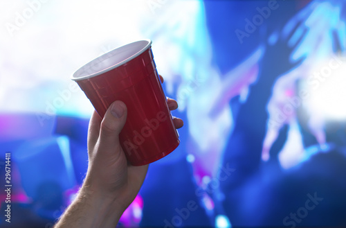 Photography Young man holding red party cup in nightclub dance floor
