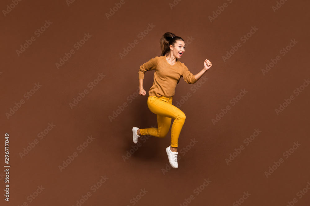 Full length body size photo of cheerful sweet pretty cute nice charming girl urgent for sales and discounted goods wearing yellow pants trousers isolated over brown pastel color background