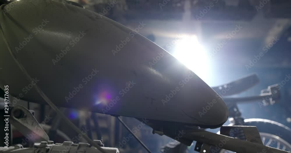 A tank on an old motorcycle fell dust in a dark garage and the morning sunlight from the window shines on the motorcycle parts A tank on an old motorcycle fell dust in a dark garage and the morning sunlight from the window shines on the motorcycle parts