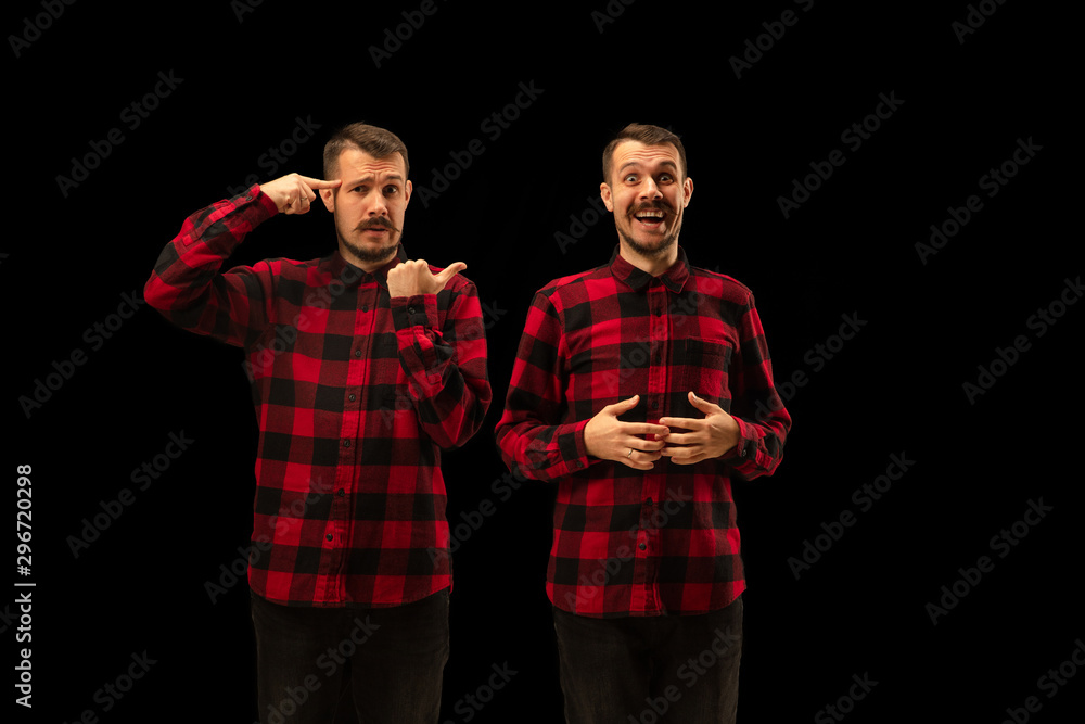 Young handsome man arguing with himself on black studio background. Concept of human emotions, mental issues, internal conflict, split personality. Half lenght portrait. Negative space. Young handsome man arguing with himself on black studio background. Concept of human emotions, mental issues, internal conflict, split personality. Half lenght portrait. Negative space.