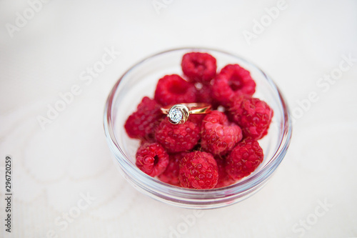 Wedding rings in bowl with raspberries top view