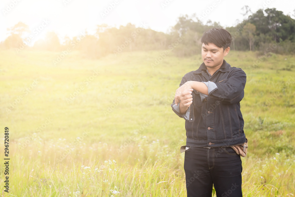 Portrait of asian man are standing on road with blurred of grass field on the background. Man in a Jean jecket are standing and enjoying the beautiful nature. Portrait of asian man are standing on road with blurred of grass field on the background. Man in a Jean jecket are standing and enjoying the beautiful nature.