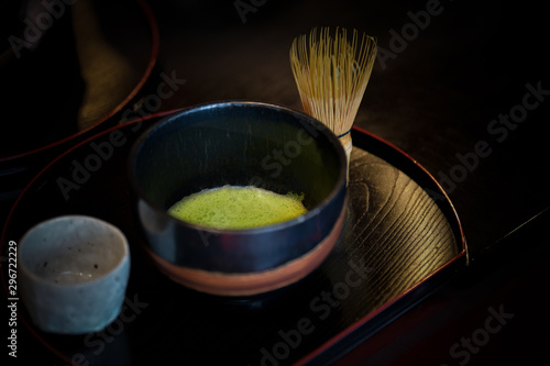 Green tea and Japanese wire whisk made of bamboo for tea ceremony and black background