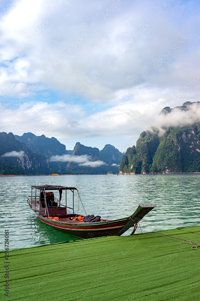 Wooden boat in lake with mountain range and clouds background