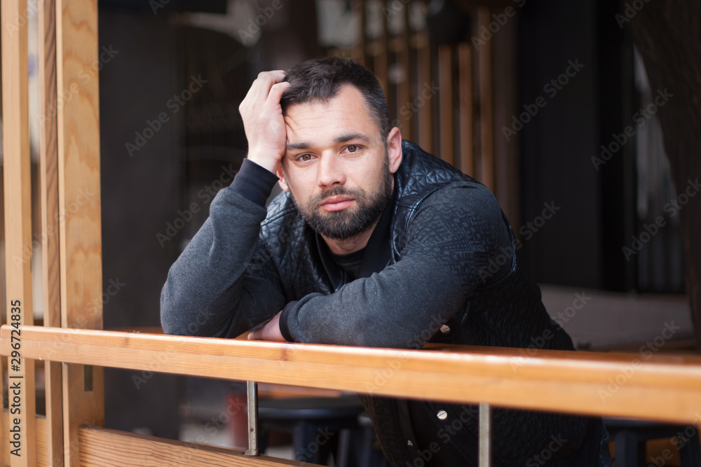 Pensive bearded young man outdoors in the afternoon in the city. Pensive bearded young man outdoors in the afternoon in the city.