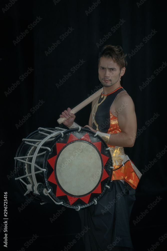 Fototapeta premium Taiko drummer with drum and drumsticks on stage on a black background