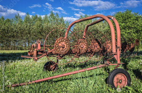 Old hay turner device on a meadow in small village in Mazowieckie Province of Poland