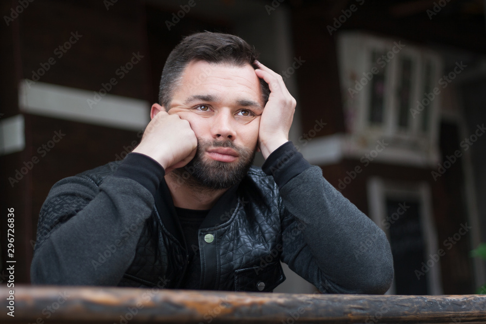 Fototapeta premium Pensive bearded young man outdoors in the afternoon in the city.