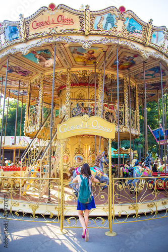 teenage girl near carousels at amusement park walking