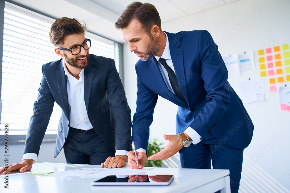 © baranq - Two business executives looking at documents and discussing in office