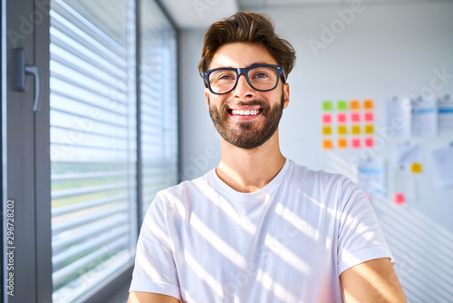 Smiling startup entrepreneur standing in office and looking away