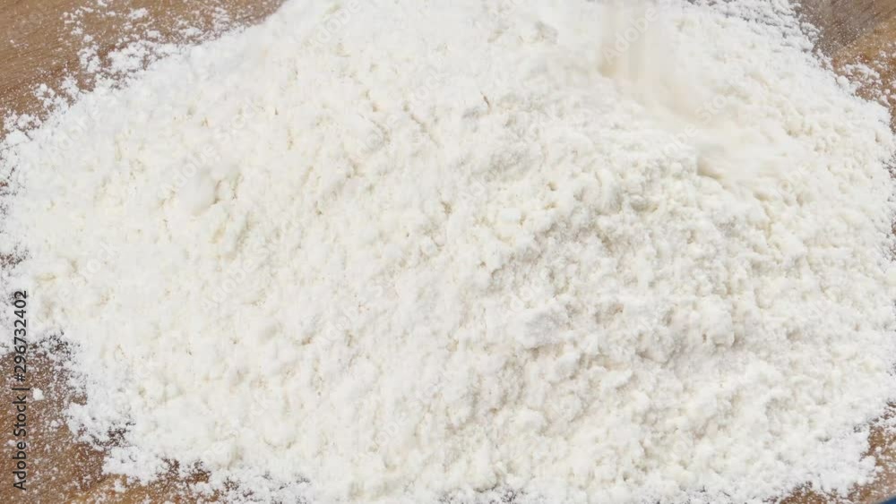 flour is falling onto a wooden cutting board flour is falling onto a wooden cutting board