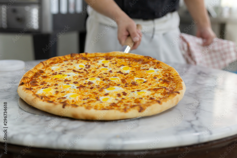 Chefs hand holding hawaiian pizza on wooden board Chefs hand holding hawaiian pizza on wooden board