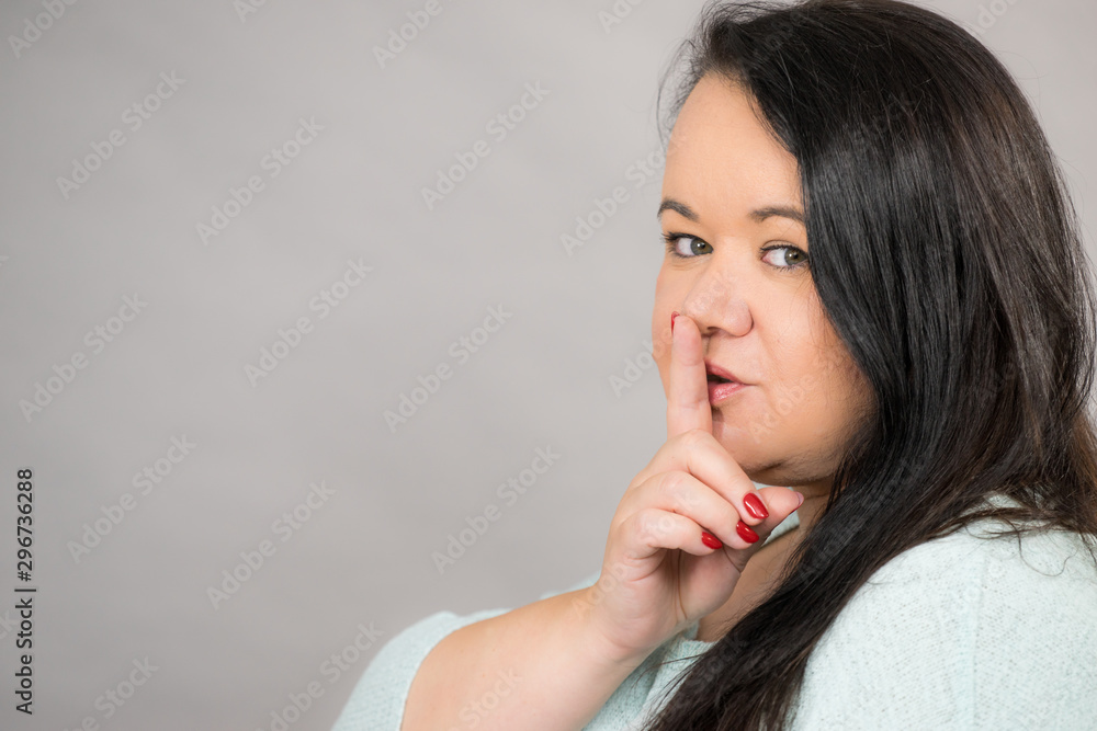 Woman asking for silence with finger on lips Woman asking for silence with finger on lips