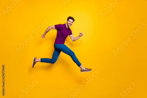 Full lenghtb body size side profile photo of hurrying urgent white casual guy running jumping in blue pants trousers purple t-shirt footwear isolated over vivid color background
