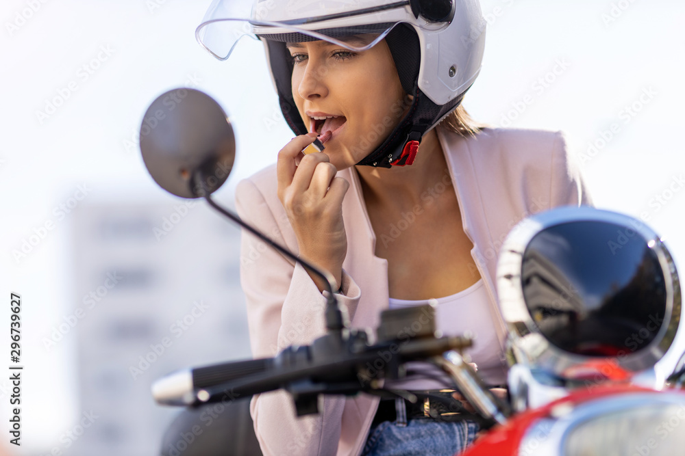 Woman on moped applying lipstick Woman on moped applying lipstick