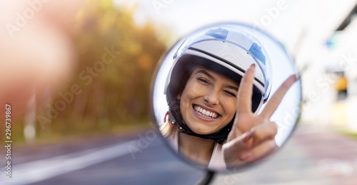 Reflection of beautiful young woman in motor scooter mirror 