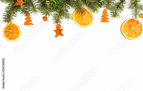 Christmas diy border - green fir branches, decorated with hfndmade dried oranges, painted cones and dried orange peel figurines on white. Zero waste christmas concept.	
