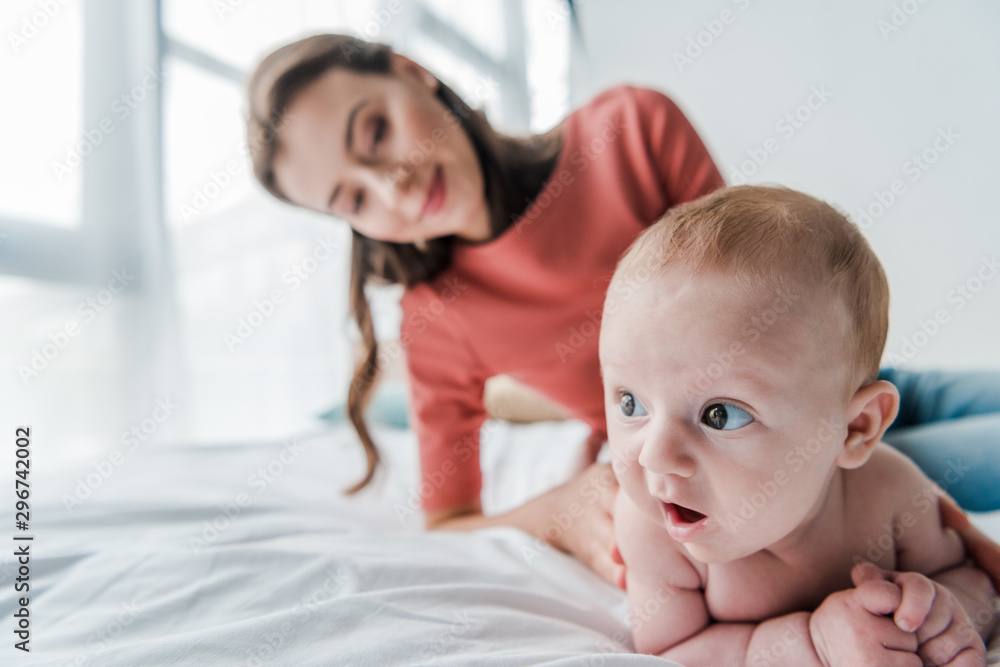 selective focus cute infant baby near happy mother in bedroom selective focus cute infant baby near happy mother in bedroom