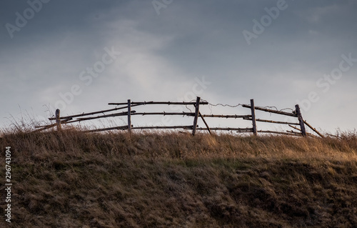 An old broken wooden fence against a gray sky.