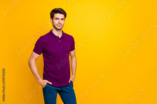 Portrait of his he nice attractive content serious guy wearing violet shirt holding hands in pockets isolated on bright vivid shine vibrant yellow color background