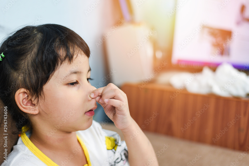 Asian little girl sick with hand holding the nose get cold and blow nose the flu season - child runny nose and sneezing blowing their nose and fevers at home Asian little girl sick with hand holding the nose get cold and blow nose the flu season - child runny nose and sneezing blowing their nose and fevers at home