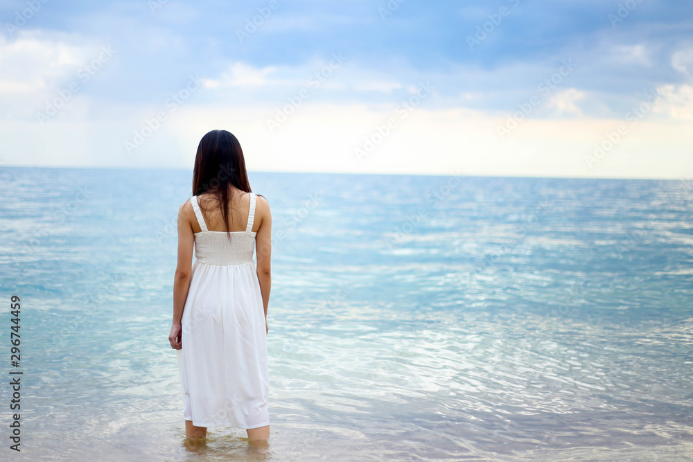 Beautiful girl young woman asia standing in water on sandy on the beach at sunset feeling sad. Beautiful girl young woman asia standing in water on sandy on the beach at sunset feeling sad.