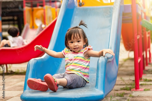 Asian child girl playing a slider toy at the playground. Happy Baby aged 2 years old.
