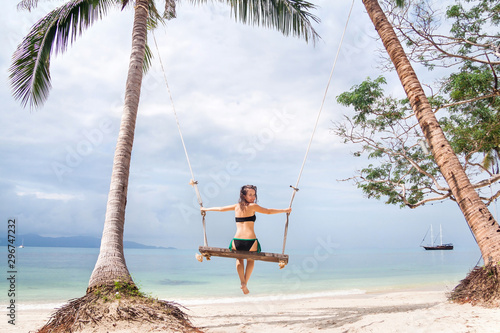 Young woman swinging on a big beach swing in Thailand