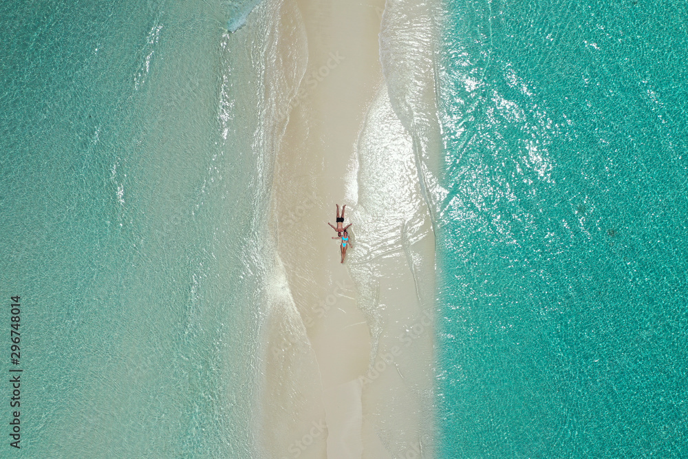Top view of romantic couple stretched on the white sand of a maldivian beach