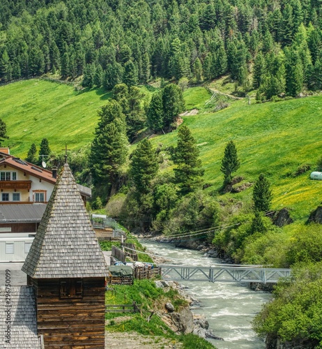 Obraz na płótnie a small bridge over the mountain stream, mountain hiking in the alps, on the alpine pasture yellow flowers are blooming w salonie