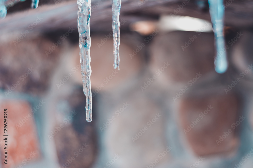 Close-up of an icicle while warming and melting ice on the roof of a house