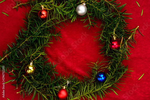 Christmas tree branches stacked in a circle for the inscription Merry Christmas on a red background.
