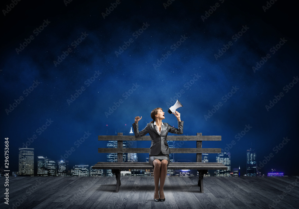 Business woman with megaphone on wooden bench