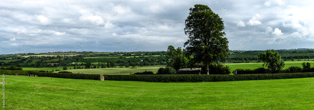 Scenic view of rolling countryside green farm fields with sheep, cow  in a background on green grass in New Grange, County Meath