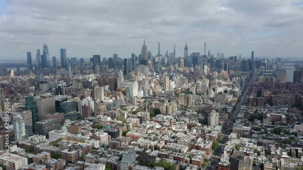 Aerial above Manhattan Island, skyline of New York with skyscrapers on horizon, clouds with sun Aerial above Manhattan Island, skyline of New York with skyscrapers on horizon, clouds with sun