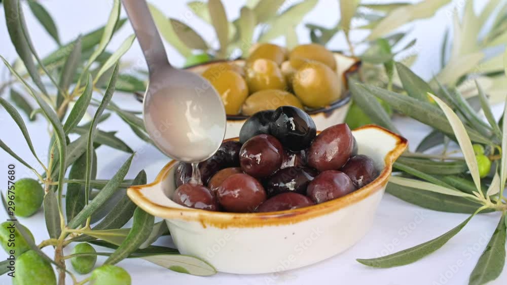 Olive oil flows through the olive. Closeup of green and black olives. A lot of berries in a cup and green leaves on a branch. Olive oil flows through the olive. Closeup of green and black olives. A lot of berries in a cup and green leaves on a branch.