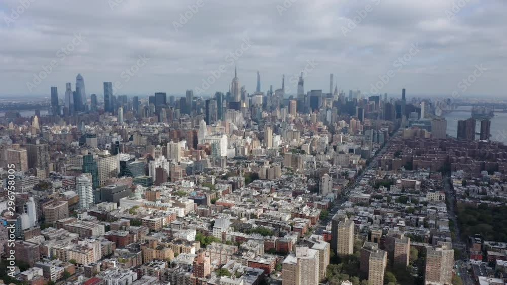 Aerial above Manhattan Island, skyline with skyscrapers on horizon, clouds with sun, New York City Aerial above Manhattan Island, skyline with skyscrapers on horizon, clouds with sun, New York City