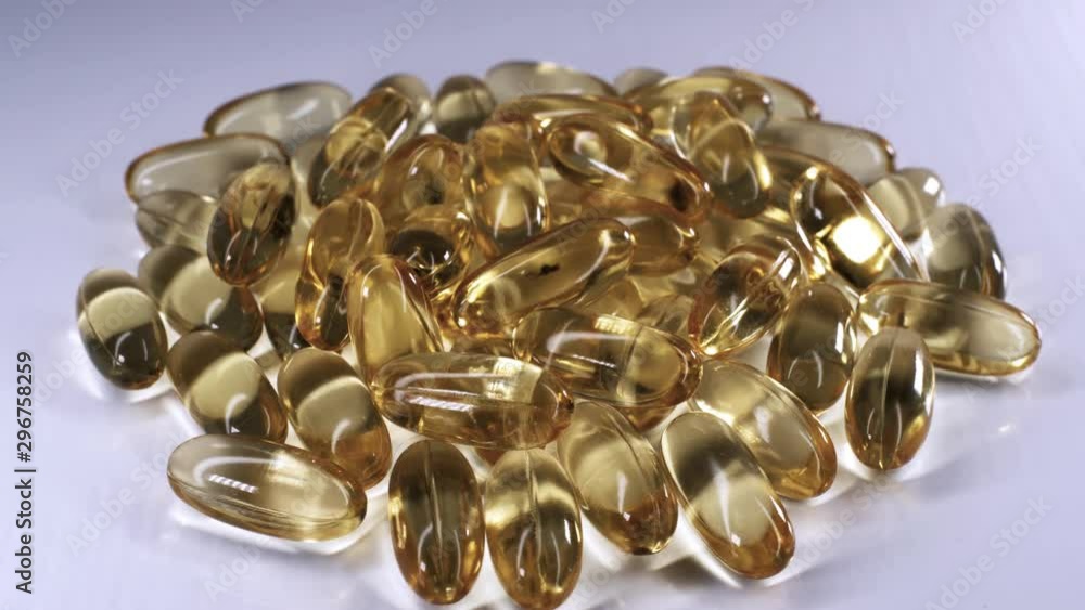 Omega 3 gold fish oil capsules, rotation background, macro. Capsule gold oil gel supplement rotating movement, Omega 3 Fish Oil, Healthcare pharmacy medical concept. Omega 3 gold fish oil capsules, rotation background, macro. Capsule gold oil gel supplement rotating movement, Omega 3 Fish Oil, Healthcare pharmacy medical concept.