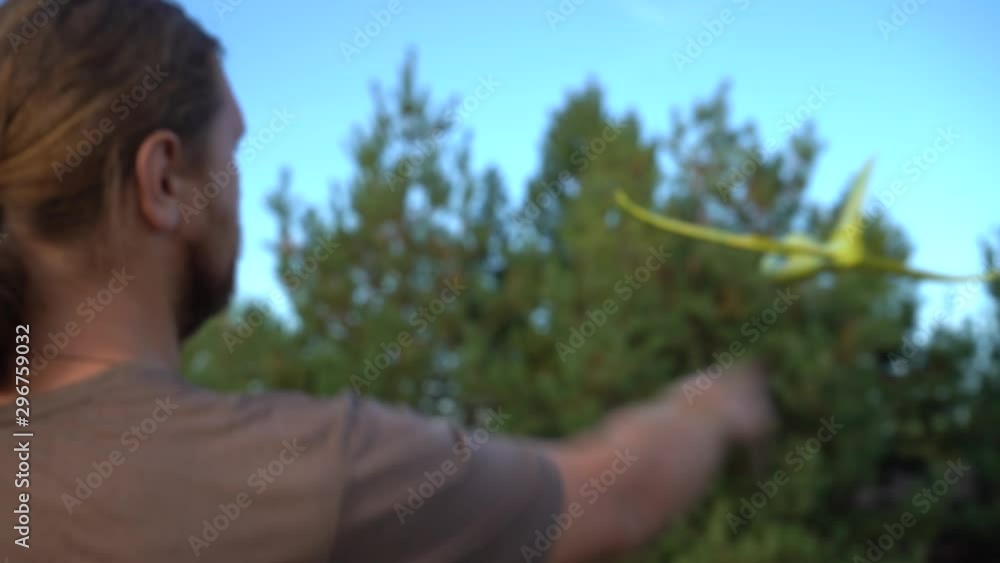 A bearded man launches a toy airplane on a background of pines and blue sky. A man plays with a toy airplane on a background of nature. A bearded man launches a toy airplane on a background of pines and blue sky. A man plays with a toy airplane on a background of nature.